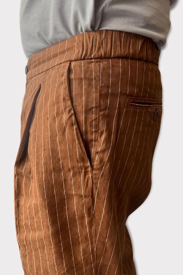 Pantalon en lin ligné marron avec poches, coupe ajustée et taille basse, style italien élégant.