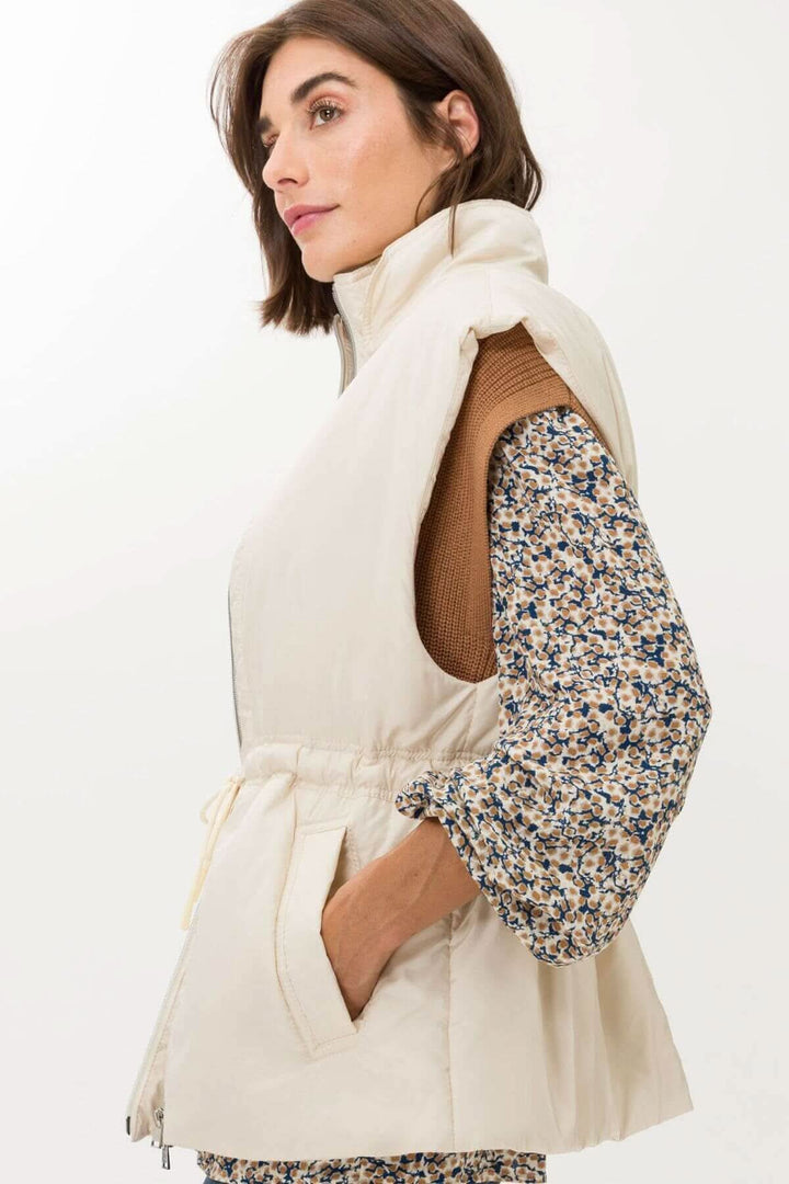 Veste sans manche Monaco beige, col haut, design élégant et pratique avec fermeture éclair à deux sens pour un style moderne.