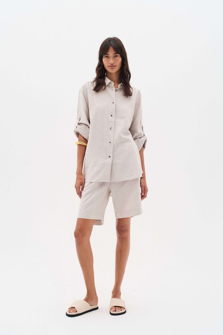 Femme portant un ensemble en lin, chemise beige et bermuda, idéal pour les journées chaudes d&