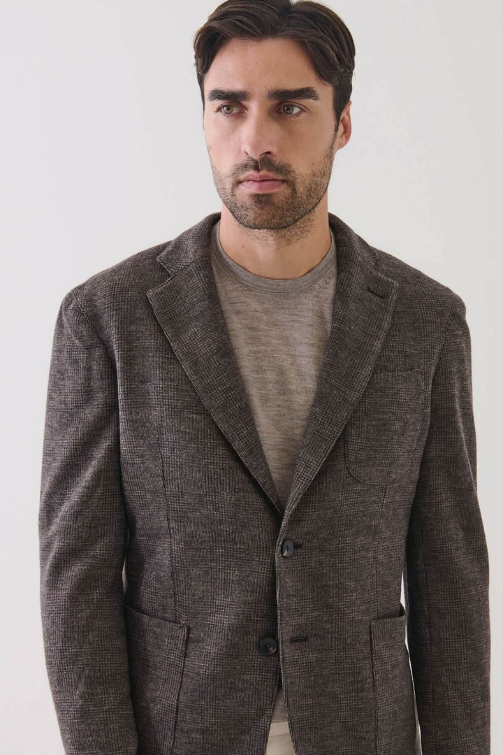 Homme portant un blazer à deux boutons en laine à carreaux, élégant et décontracté, confectionné en Italie avec un motif prince-de-galles subtil.