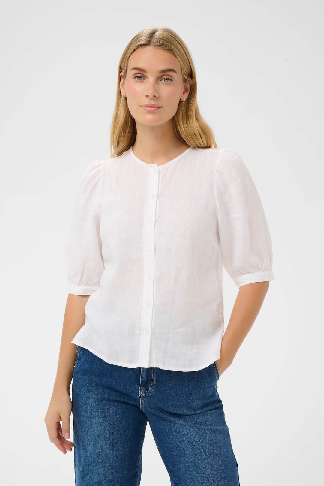 Femme portant Blouse Azra blanche avec manches légèrement bouffantes et coupe droite, style intemporel et féminin.