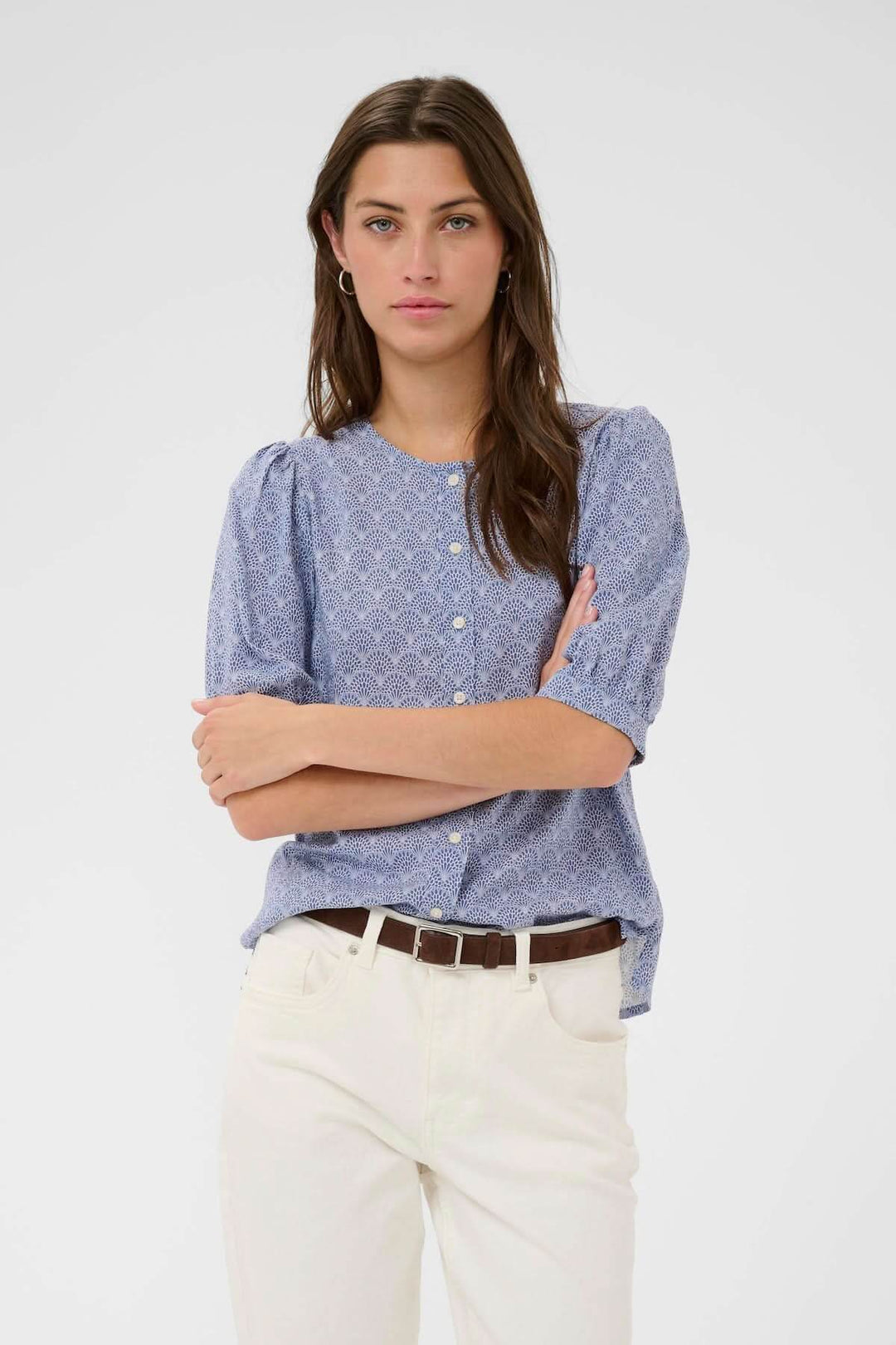 Blouse Azra avec imprimé fin, manches bouffantes et coupe droite, portée avec un pantalon blanc pour une allure féminine et versatile.