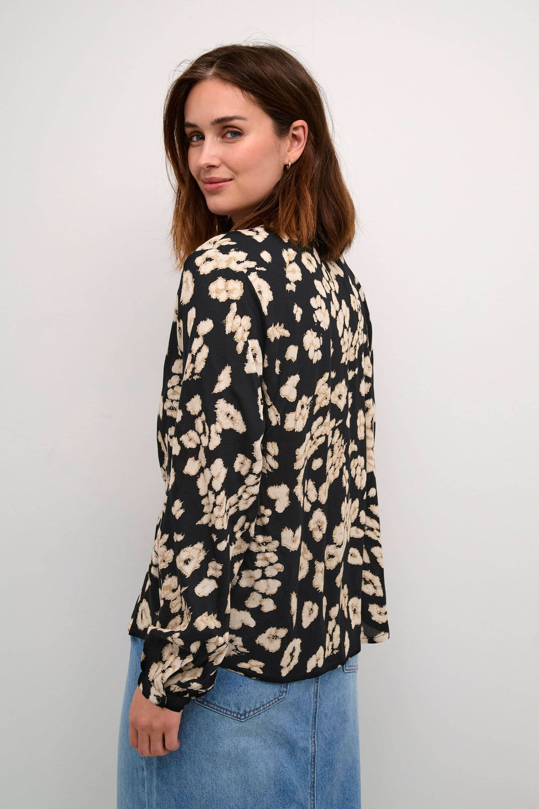 Femme portant une blouse en imprimé léopard avec une coupe standard et manches longues, affichant un style audacieux.