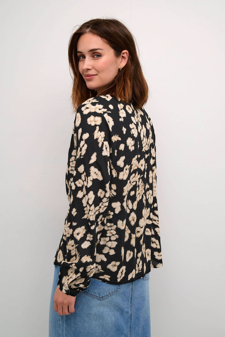 Femme portant une blouse en imprimé léopard avec une coupe standard et manches longues, affichant un style audacieux.