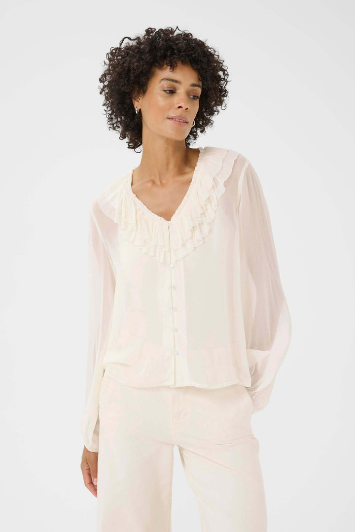 Blouse Sanaz élégante avec col volanté, manches longues transparentes, style chic et sophistiqué.