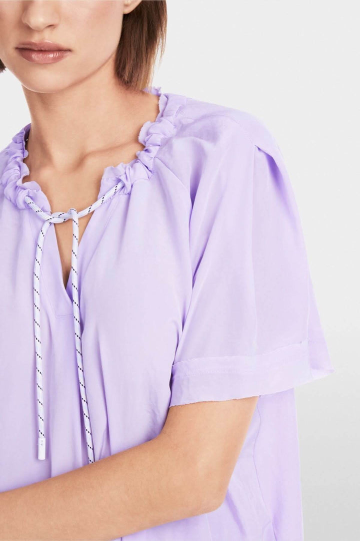 Blouse lilas avec col fendillé et cordon de serrage, coupe ample et décontractée, idéale pour un look casual.