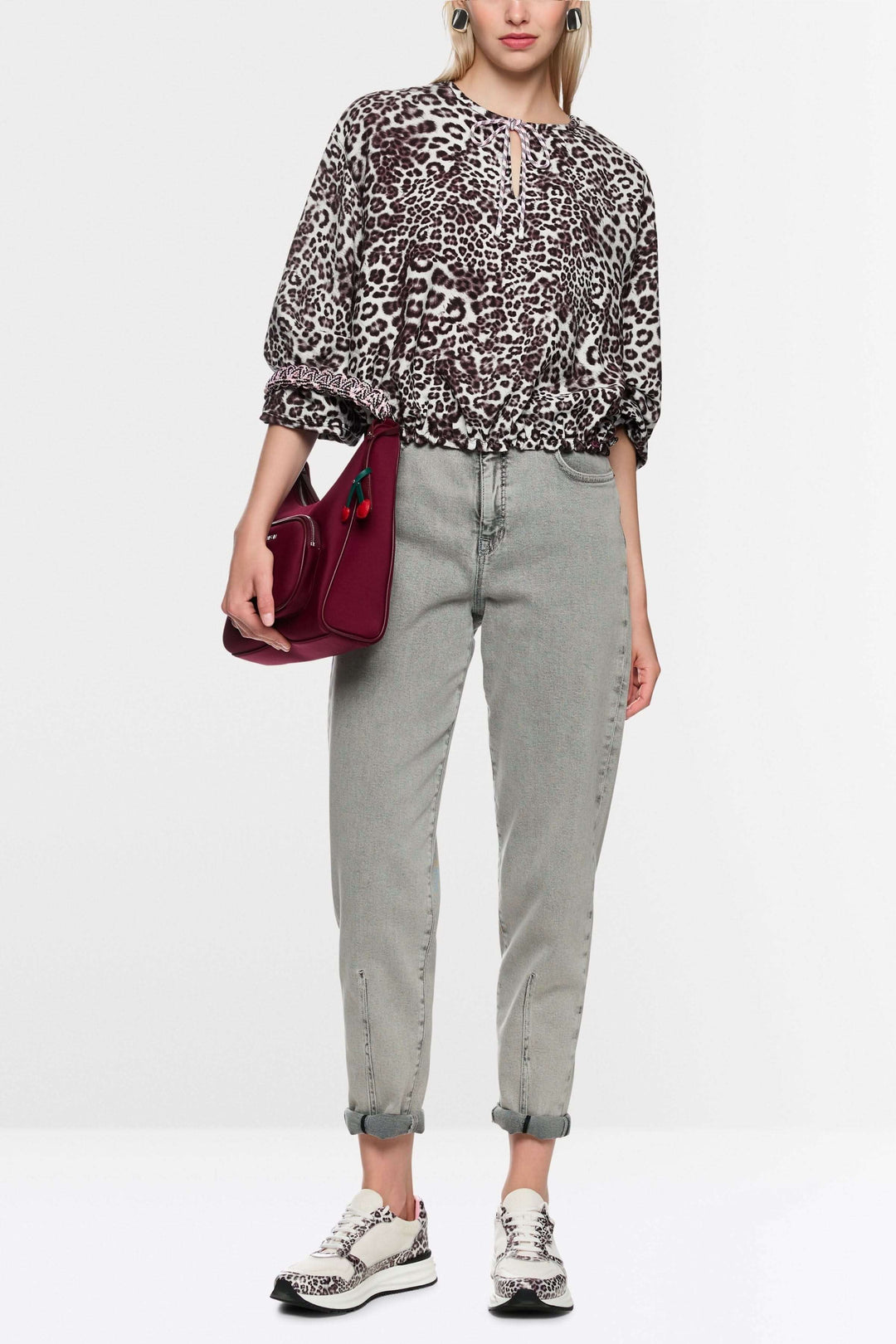 Blouse avec imprimé léopard ample à encolure en V et cordon de serrage, portée avec un jean et des baskets pour un look moderne.