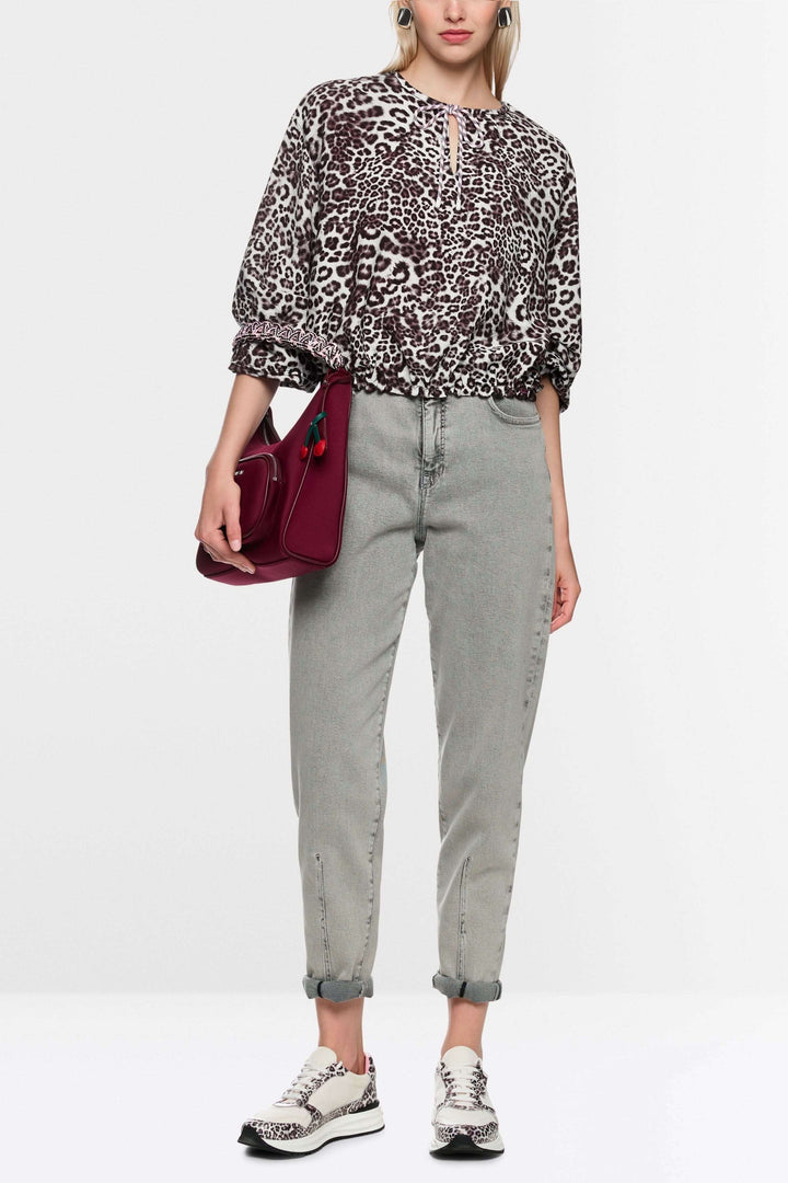 Blouse avec imprimé léopard ample à encolure en V et cordon de serrage, portée avec un jean et des baskets pour un look moderne.