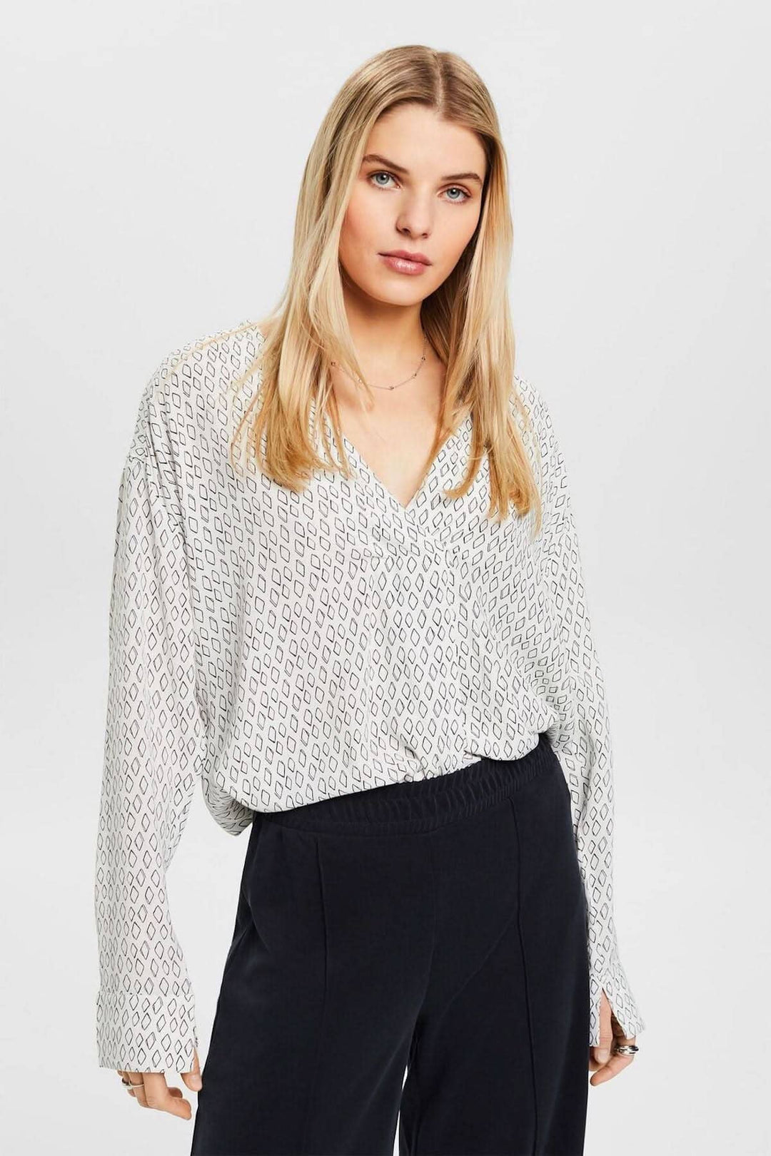 Chemisier col V ample en tissu crêpe texturé, porté sur pantalon noir, style décontracté et élégant.