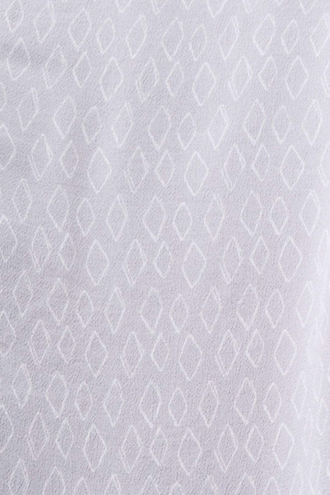 Tissu crêpe texturé blanc avec motif géométrique en losanges, utilisé pour un blouse col V.