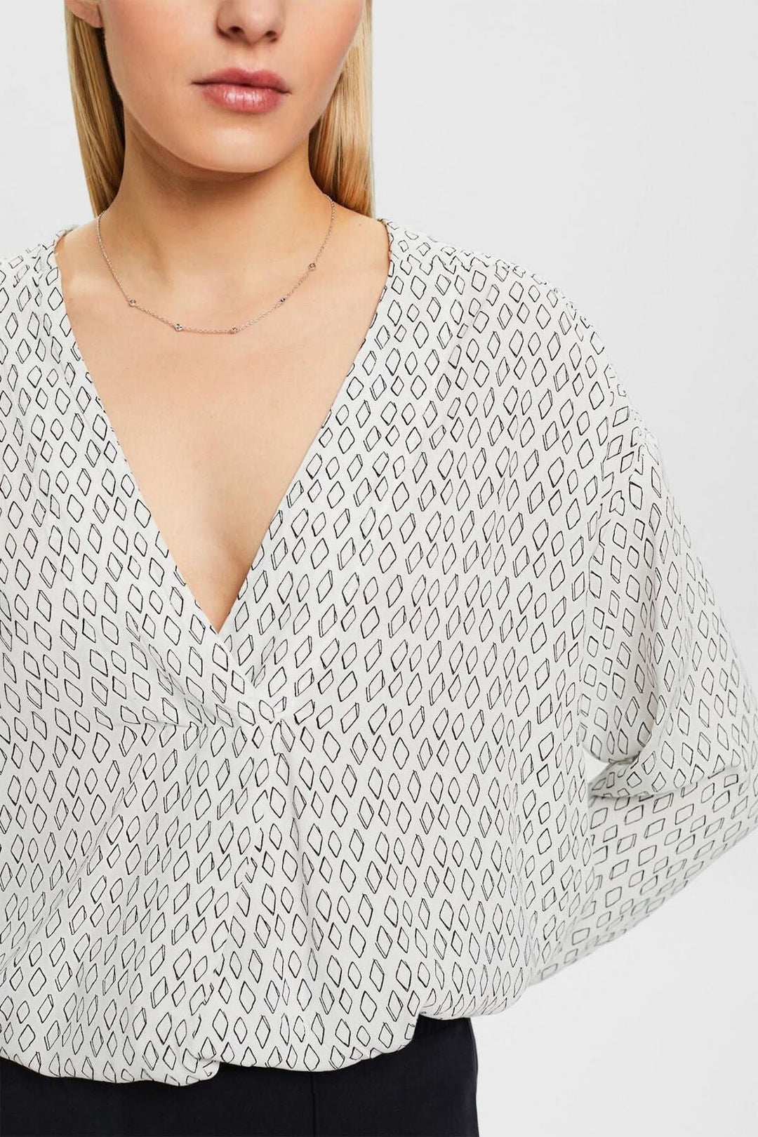 Blouse col V en tissu crêpe texturé avec imprimé géométrique, décolleté profond et coupe ample.