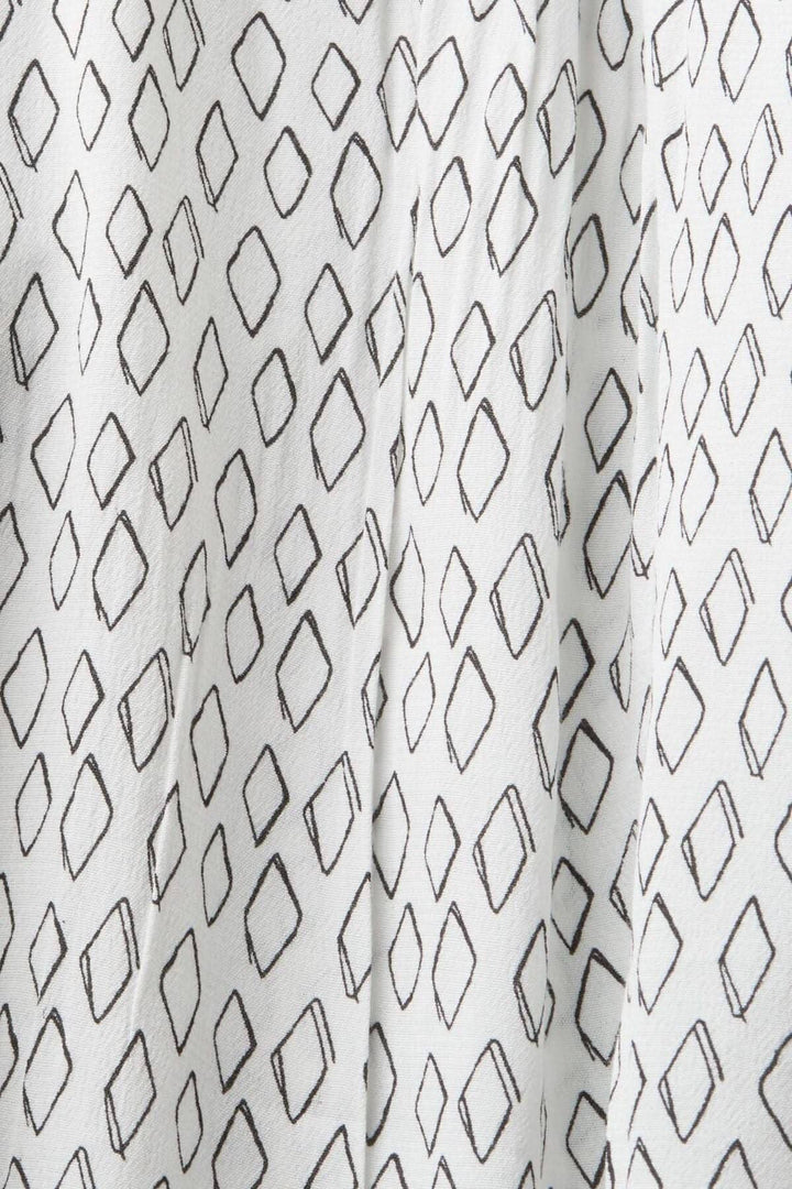 Tissu crêpe texturé blanc avec motifs en losanges noirs, idéal pour un chemisier décontracté.