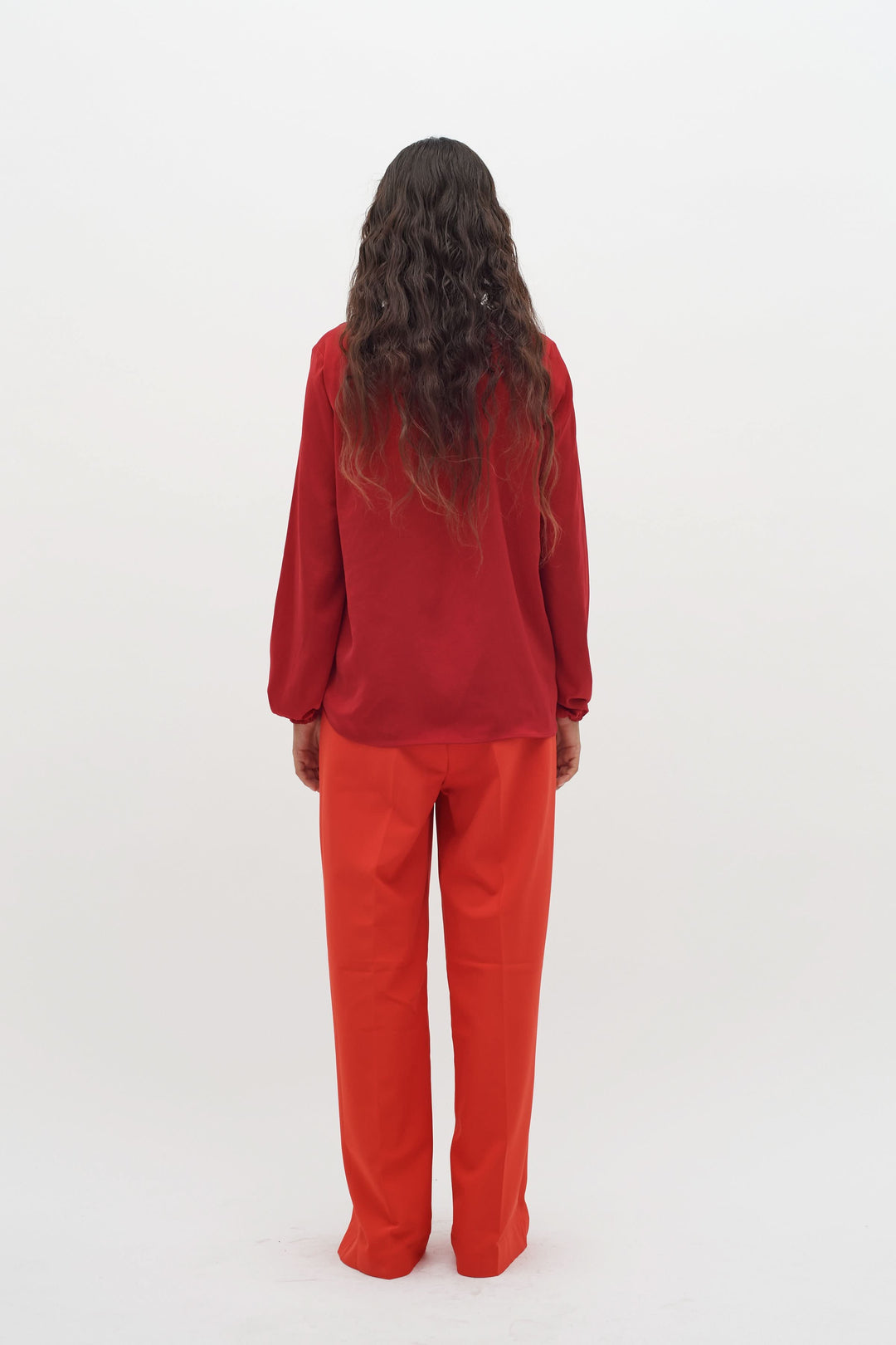Blouse col en V rouge portée avec un pantalon orange, vue arrière, style moderne et élégant.