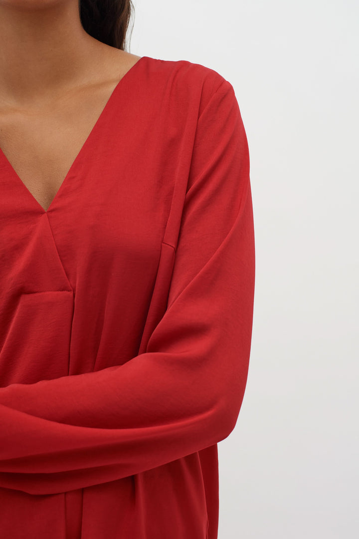 Blouse col en V Rinda en rouge, avec des manches longues et une coupe ample, parfaite pour un look sophistiqué.