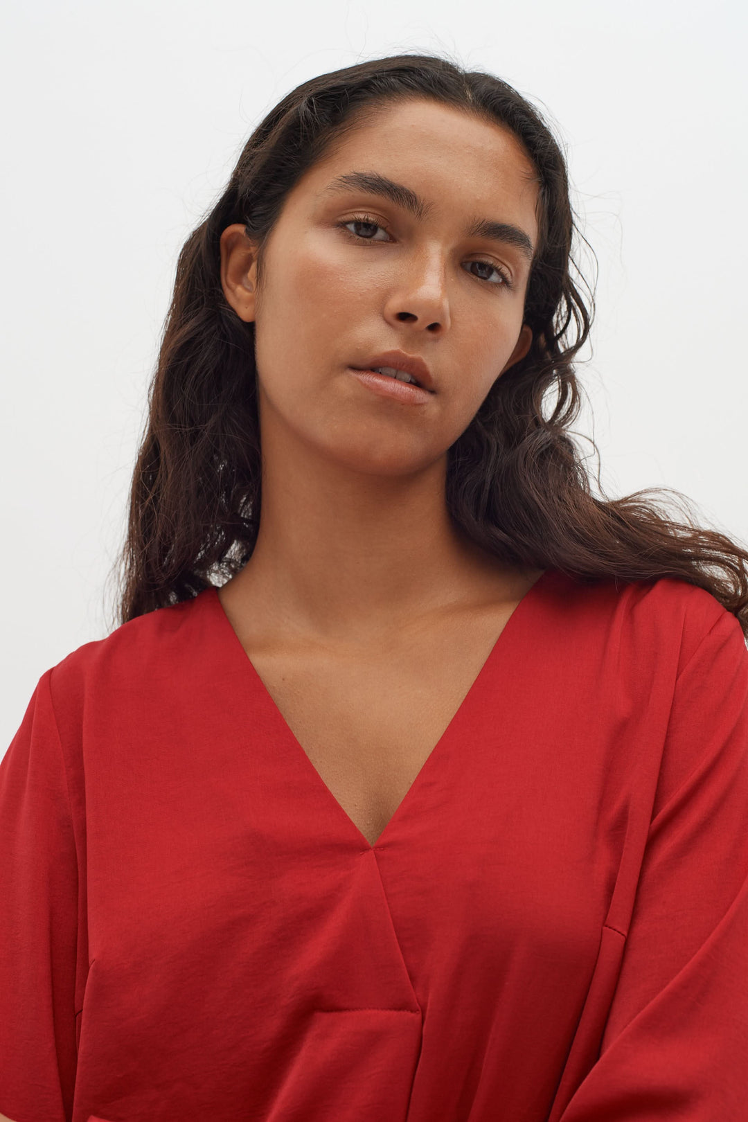 Blouse col en V Rinda rouge avec manches longues, tenue moderne et élégante.