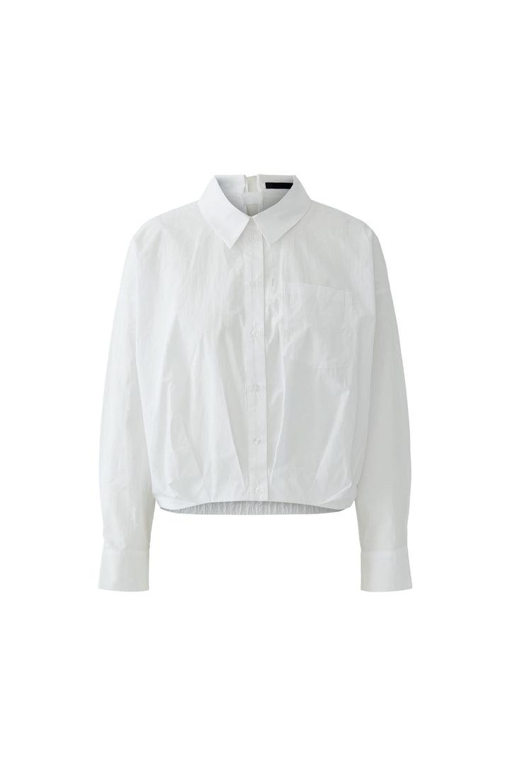 Blouse coupe moderne avec détails minimalistes, base élastiquée et col chemise classique pour un style structuré et contemporain.