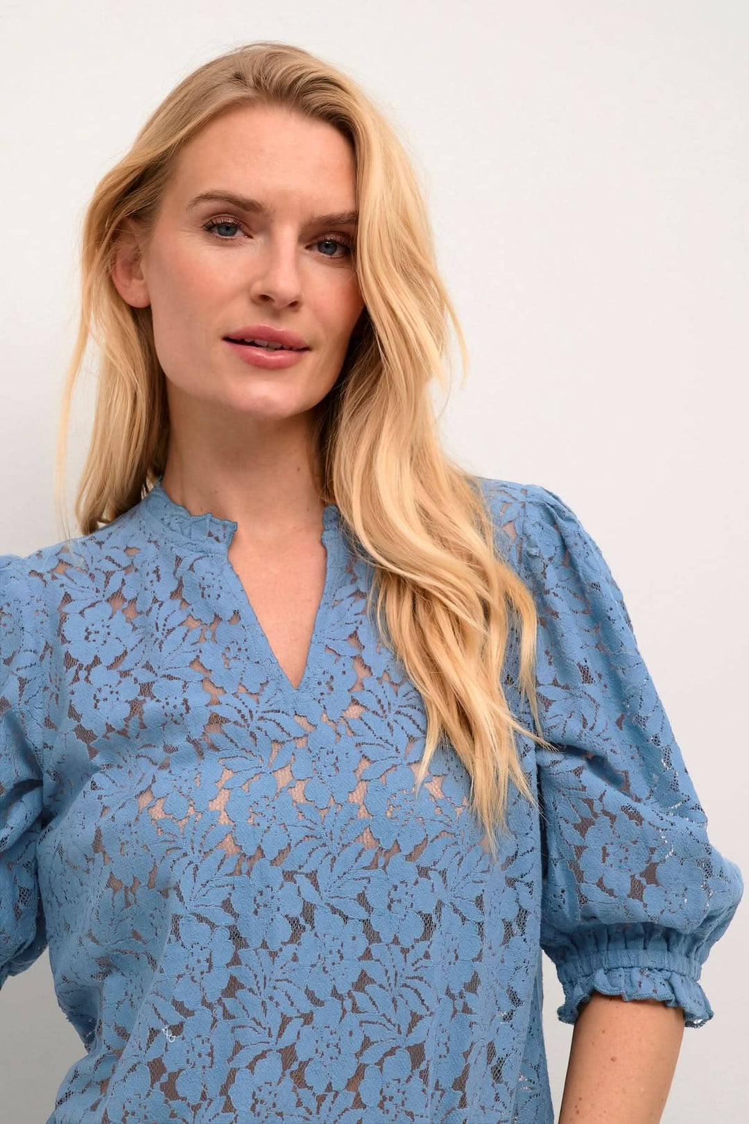 Blouse de Kaspis en bleu avec motifs floraux, manches bouffantes et finition en maille, idéale pour le travail ou les sorties.