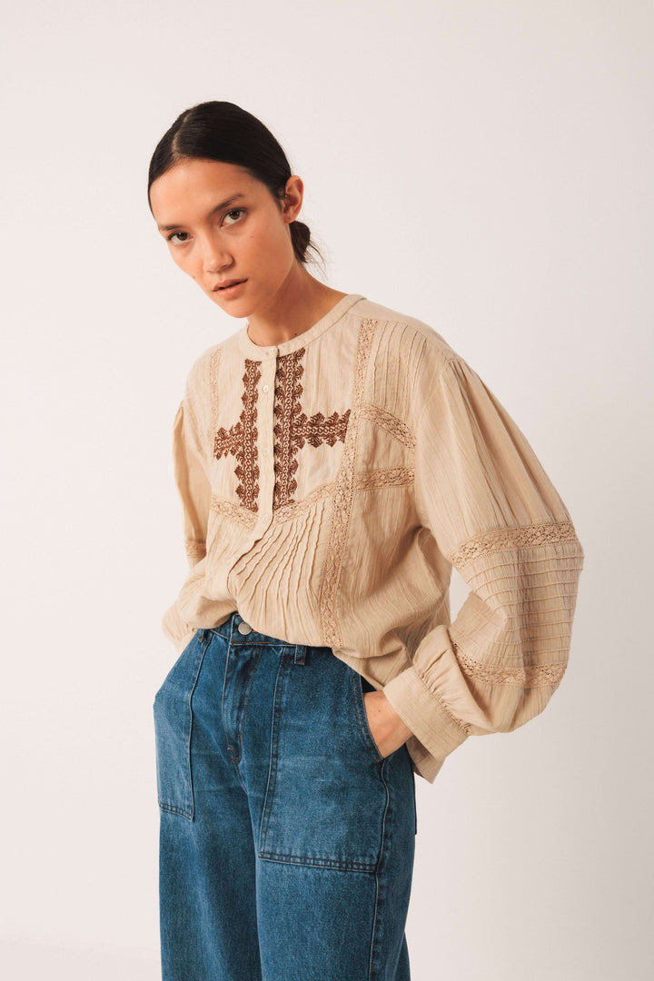 Blouse ethnique brodée beige avec broderies et manches longues, style bohème, portée avec un jean décontracté.