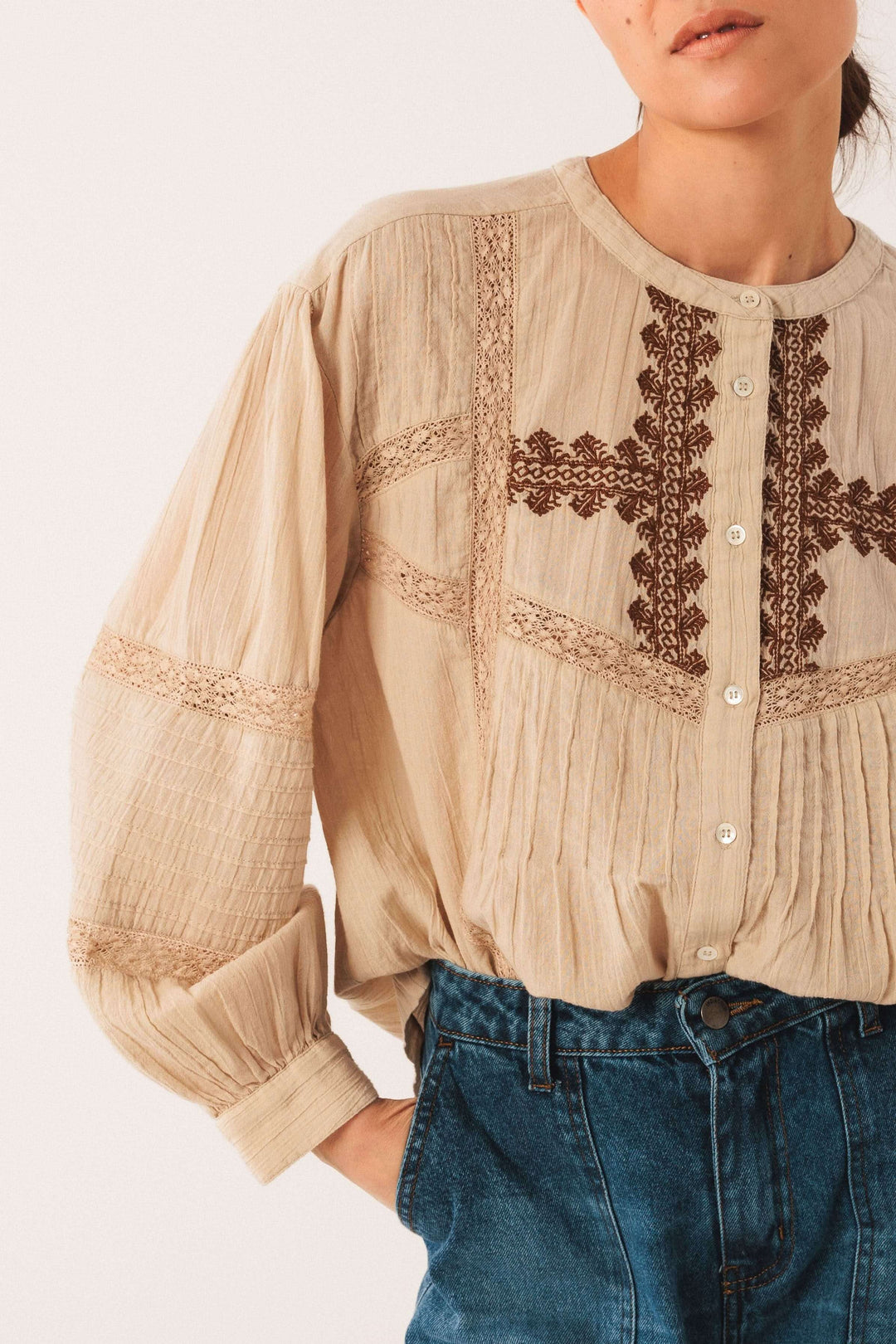 Blouse ethnique brodée avec manches longues bouffantes et broderies raffinées, style bohème, portée avec un jean. Confort et élégance.