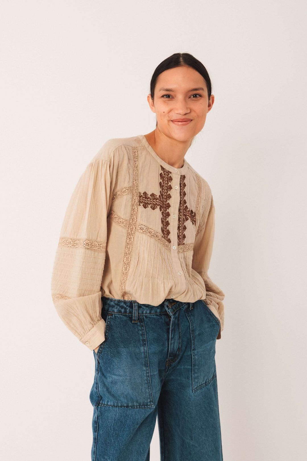 Femme portant une blouse ethnique brodée avec des broderies raffinées et une coupe ample, manches bouffantes, associé à un jean.