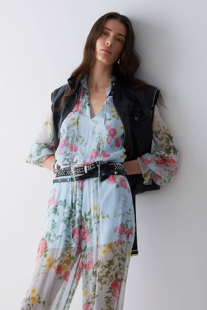 Femme portant une blouse fluide à imprimé floral, style romantique avec manches légères, encolure en V et motif fleuri.