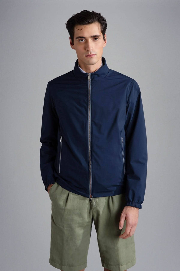 Homme portant une blouson imperméable réversible de couleur bleu marine avec des shorts clairs.