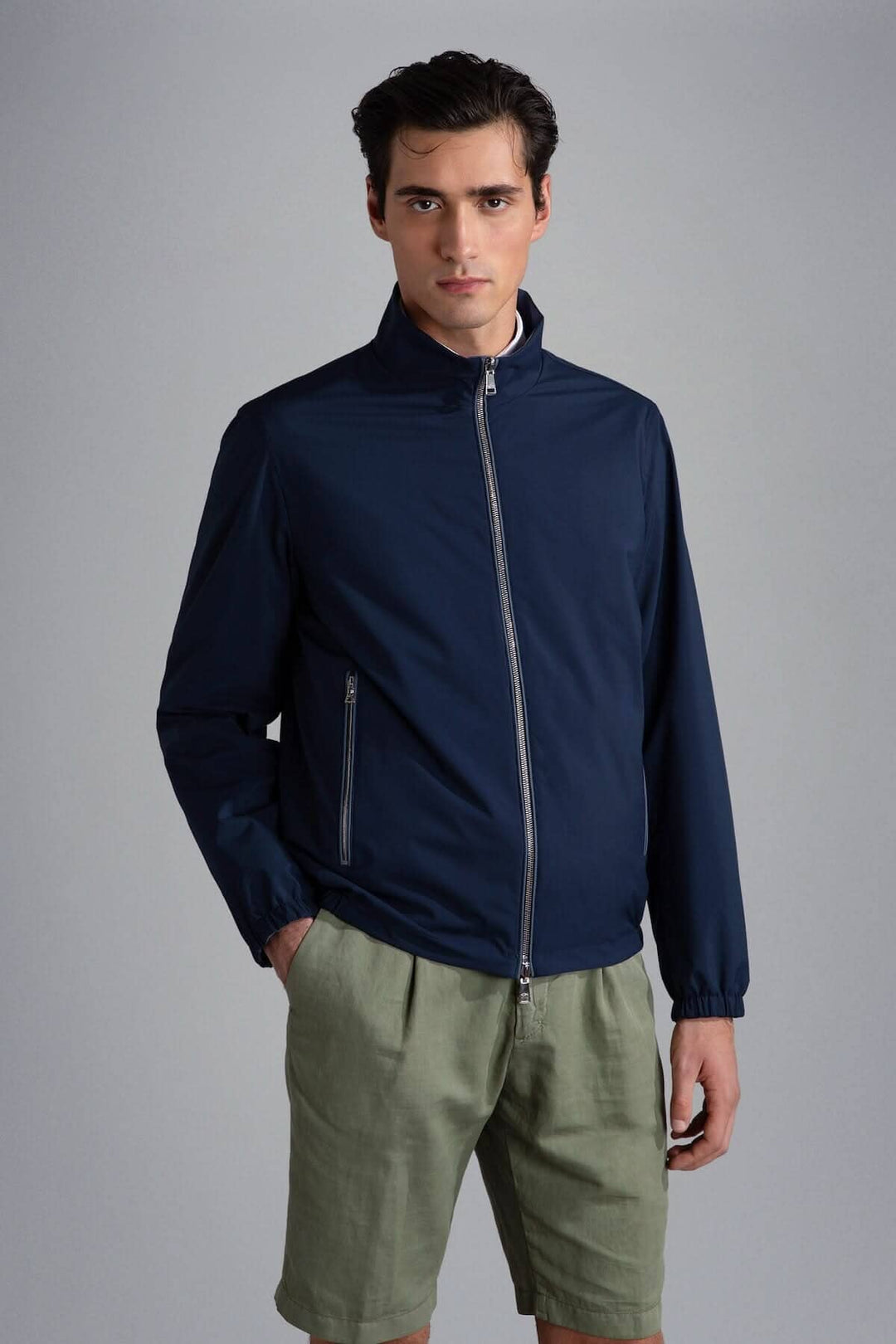 Homme portant un blouson imperméable réversible bleu marine, avec un look moderne et décontracté.