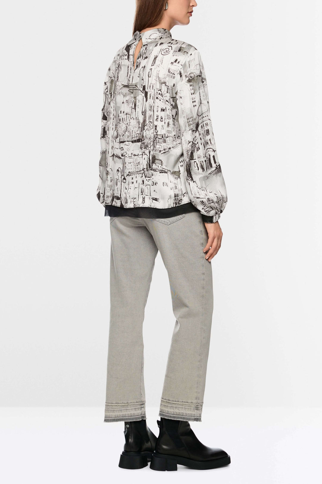 Femme portant une Blouse à imprimé CITY avec motif artistique urbain, manches longues et col montant, associée à un pantalon sobre.