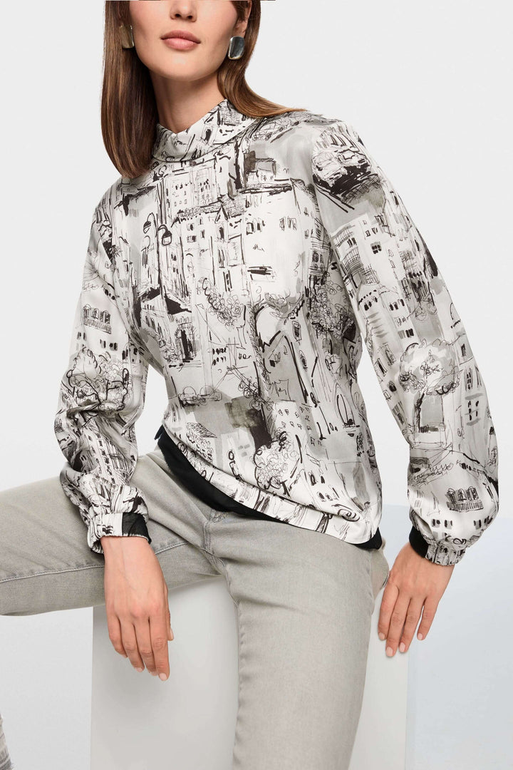 Blouse à imprimé CITY avec motif urbain artistique et manches longues pour un look élégant, présentée avec un pantalon sobre.