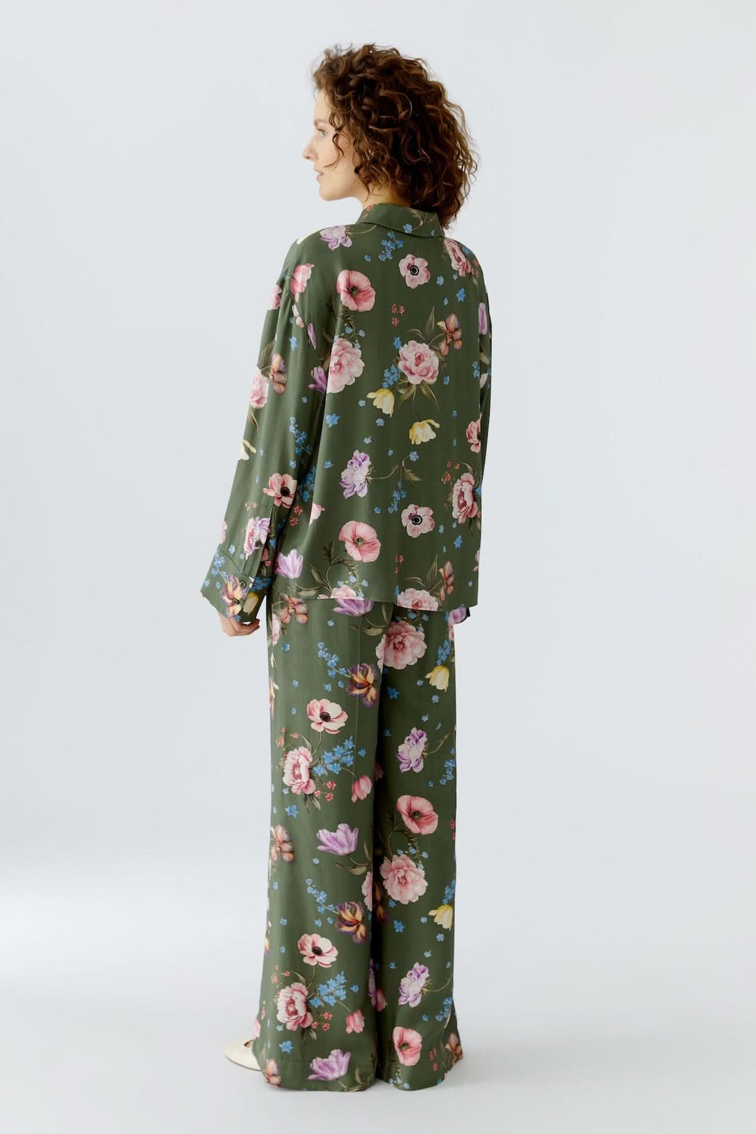 Femme portant une blouse à imprimé floral fluide avec manches longues et col chemise classique, design féminin et moderne.