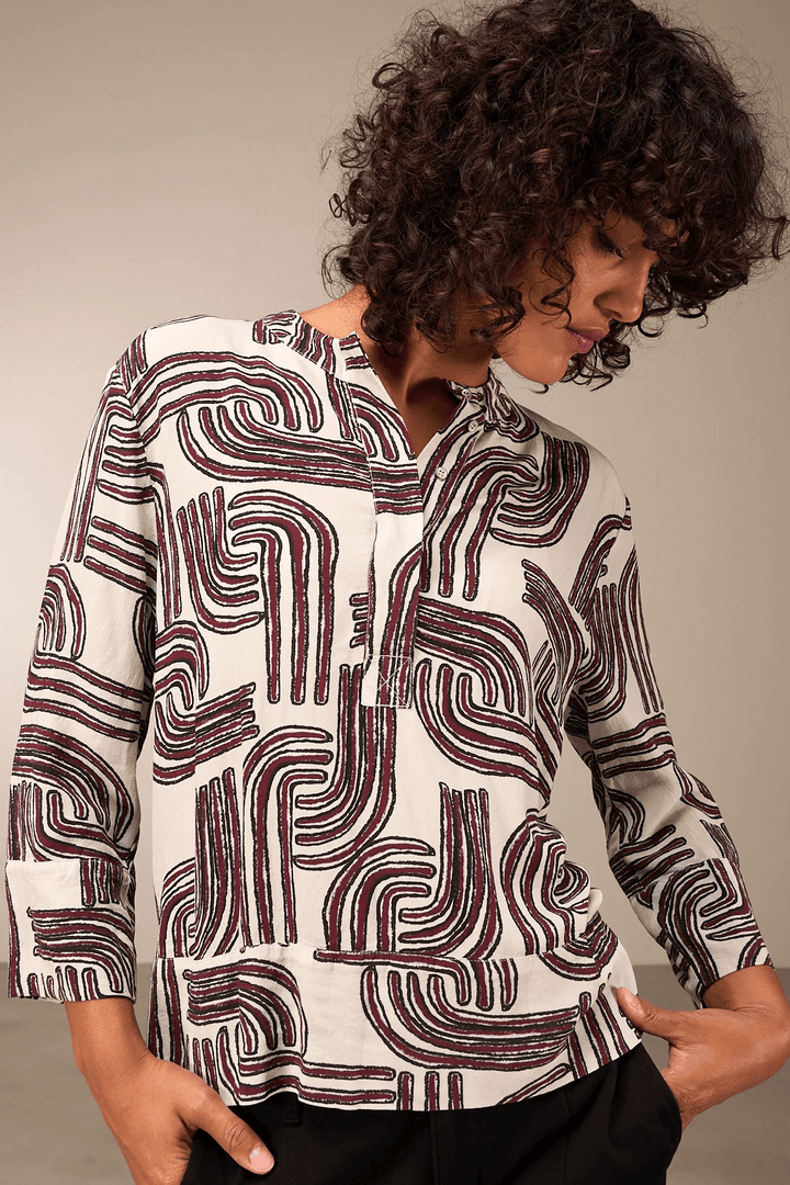Blouse à manches 3/4 avec tissu fluide et encolure ronde, offrant une allure moderne et élégante, portée par modèle.