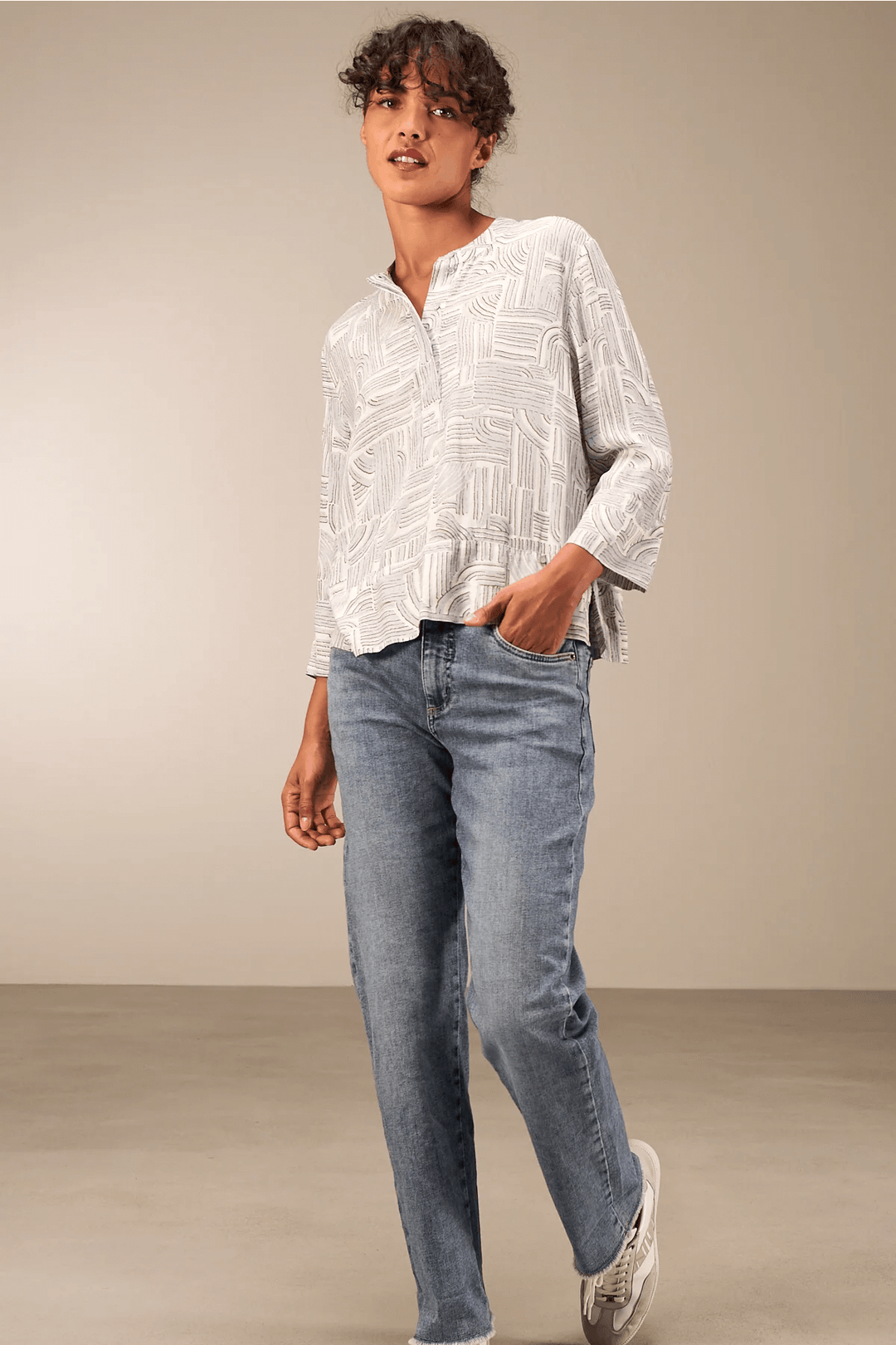 Blouse à manches 3/4 décontractée en tissu fluide avec encolure ronde, portée avec jean pour look moderne et confortable.
