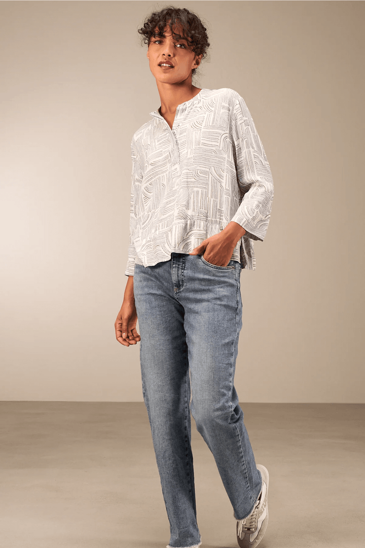 Blouse à manches 3/4 décontractée en tissu fluide avec encolure ronde, portée avec jean pour look moderne et confortable.