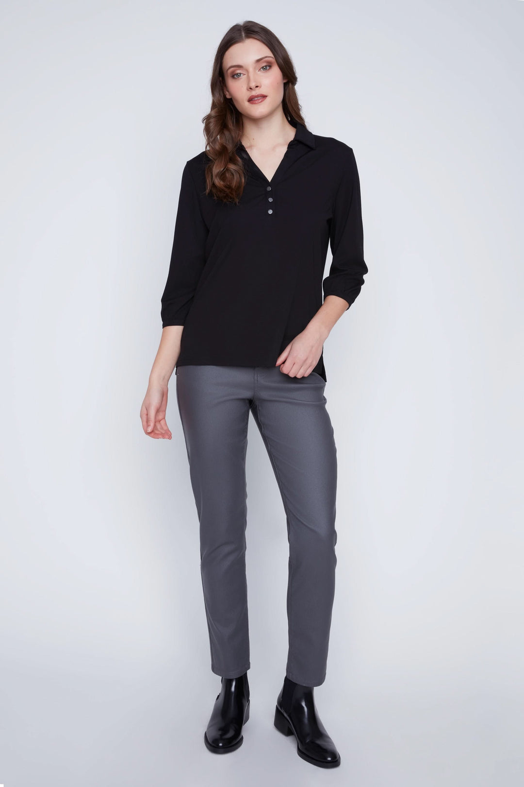 Femme portant une Blouse manches 3/4 noire avec encolure en V et boutons, associée à un pantalon gris pour un look chic et polyvalent.