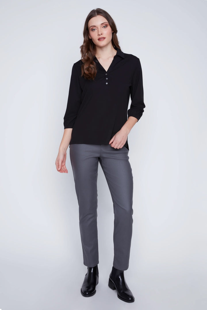 Femme portant une Blouse manches 3/4 noire avec encolure en V et boutons, associée à un pantalon gris pour un look chic et polyvalent.