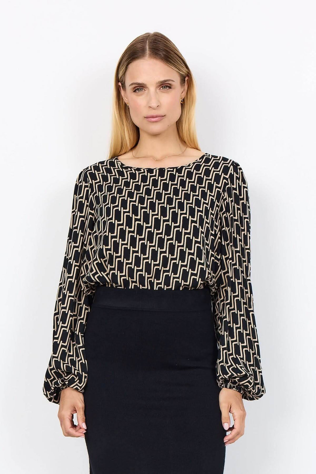 Blouse à motif graphique géométrique avec encolure ronde et manches bouffantes, portée avec une jupe crayon.