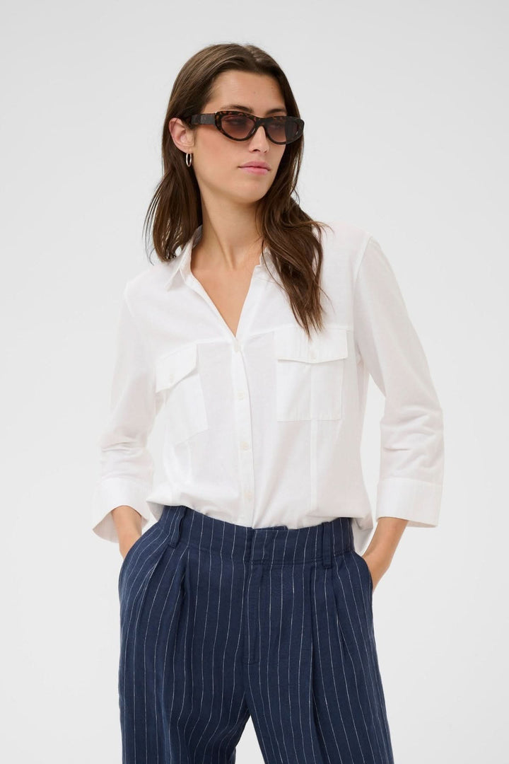 Blouse à poches utilitaires Anise portée par une femme, coupe fluide et moderne avec col chemise classique pour un style soigné quotidien.