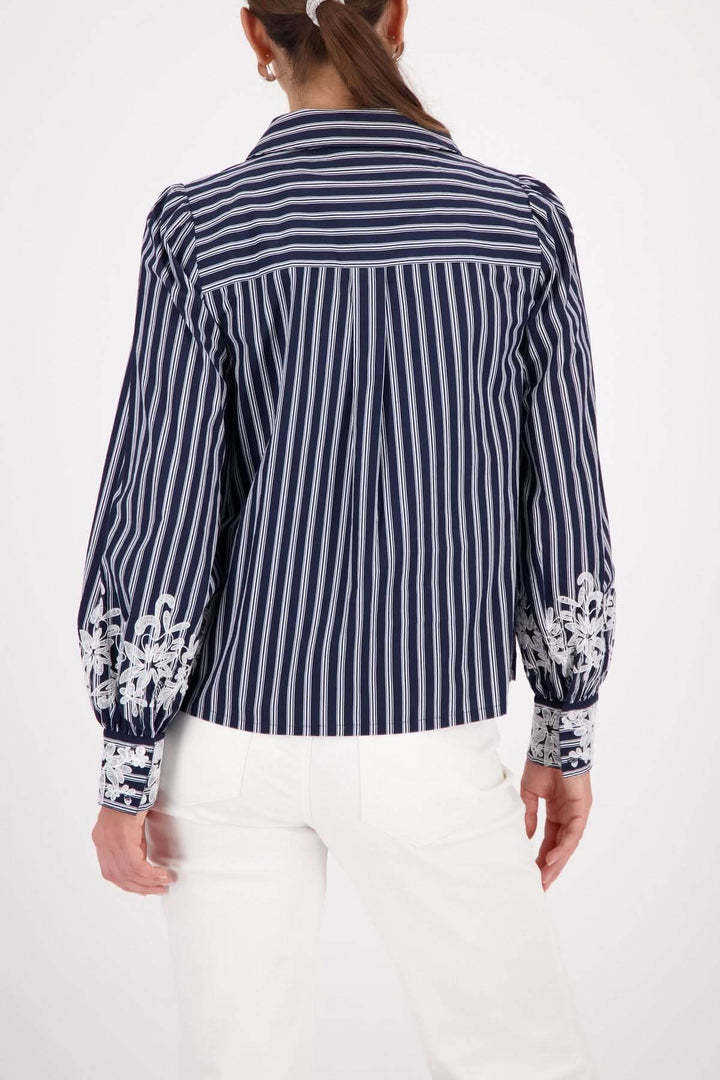 Blouse à rayures avec broderies florales aux poignets, vue arrière, femme portant un pantalon blanc.