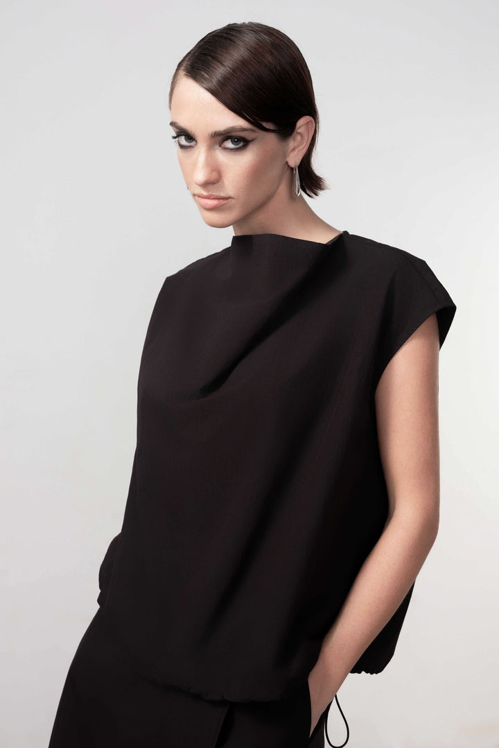 Blouse sans manches avec design épuré et drapé subtil, coupe droite fluide pour une élégance moderne, modèle féminin en noir.