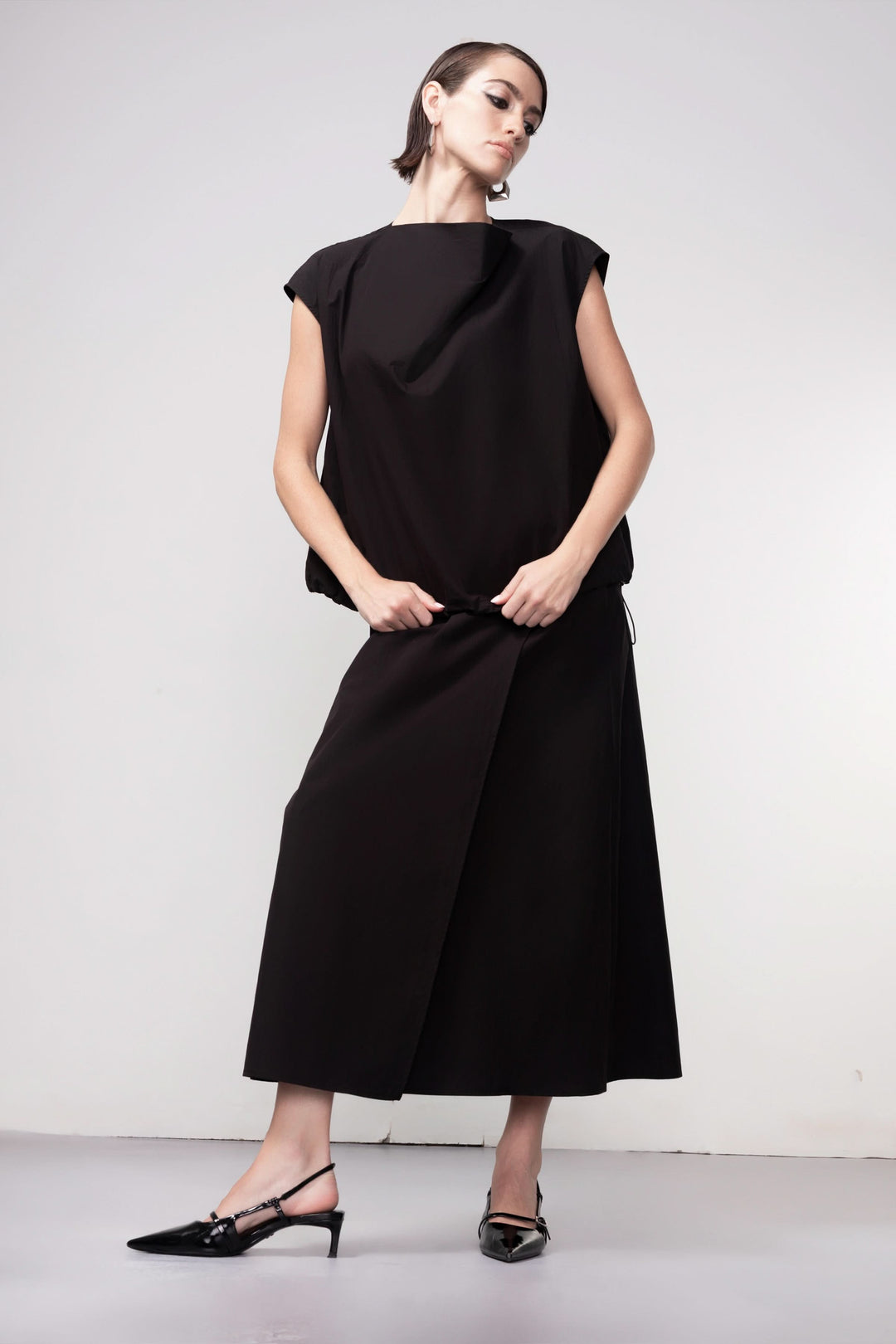 Femme portant une blouse sans manches avec design épuré et coupe fluide, illustrant élégance et modernité.