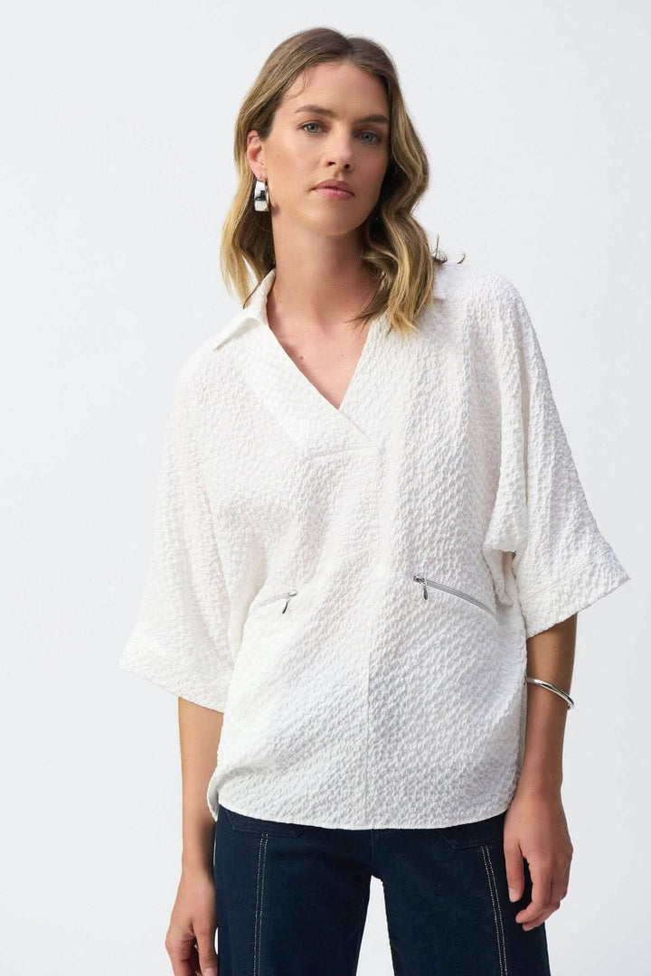 Blouse texturée gaufrée blanche avec encolure en V et manches courtes, poches avec fermeture éclair.