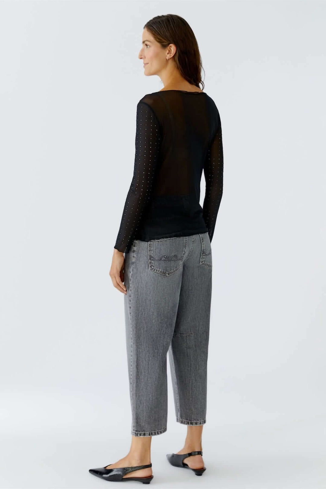 Femme portant un body transparent à manches longues avec studs, coupe ajustée et élégante, idéal pour une allure sophistiquée.