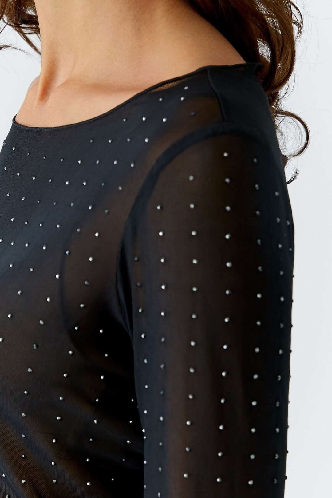 Body transparent à manches longues avec petits studs métalliques sur maille fine, idéal pour une allure élégante et moderne.