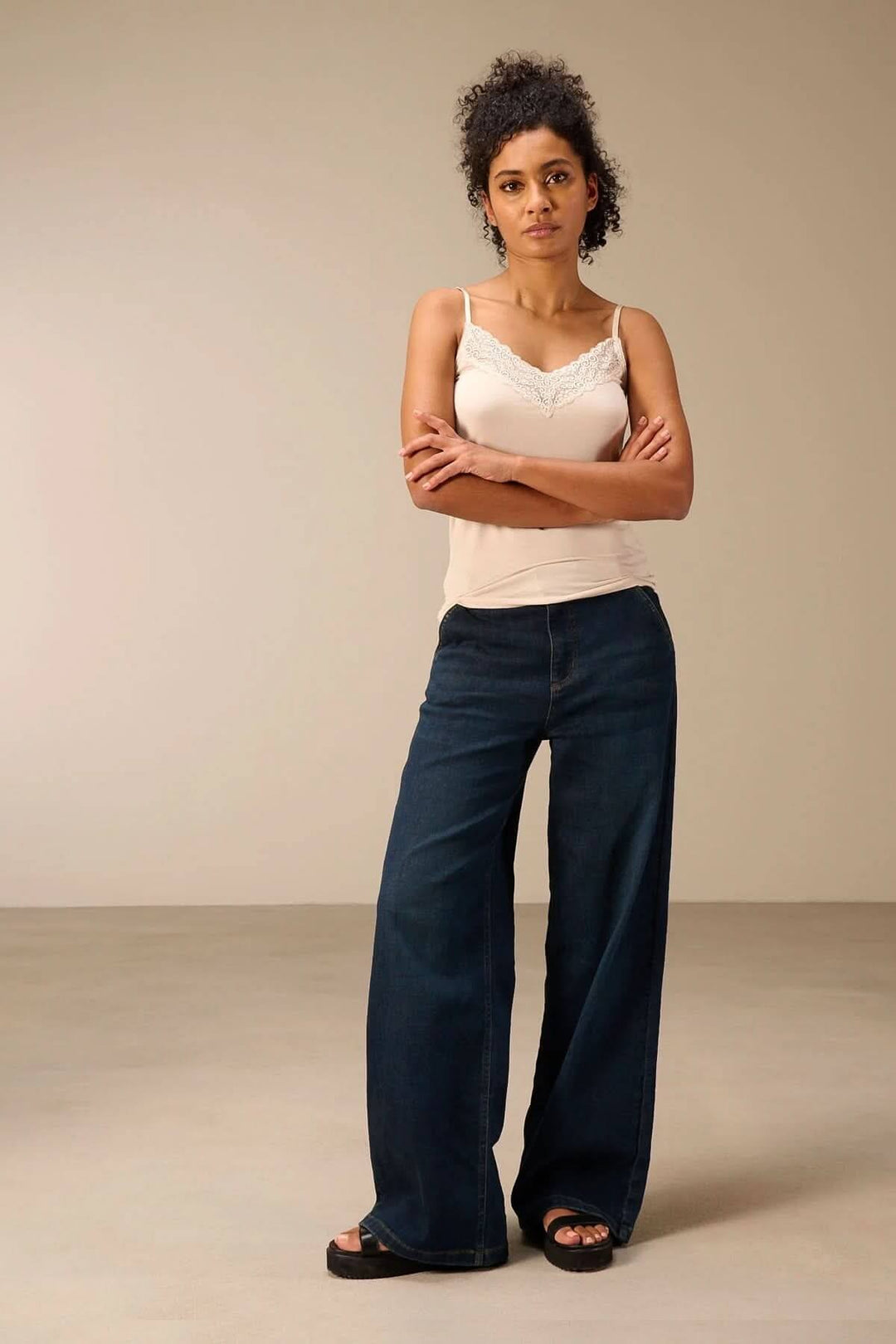 Femme portant une camisole à bretelles avec dentelle, style élégant et confortable, parfaite pour superposer avec d'autres vêtements.