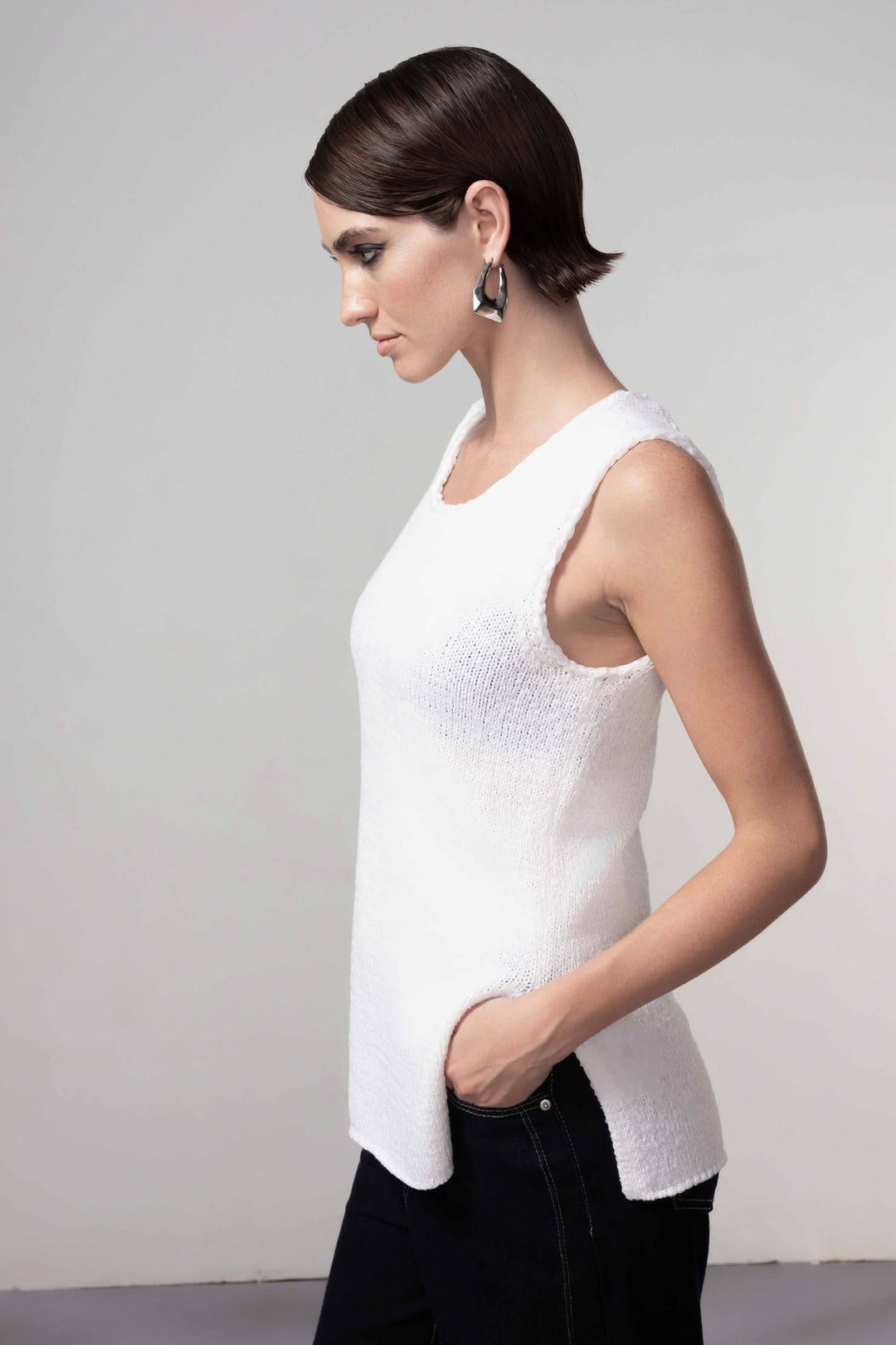 Femme portant une camisole en maille blanche, coupe droite et encolure arrondie, idéale pour une tenue élégante et minimaliste.