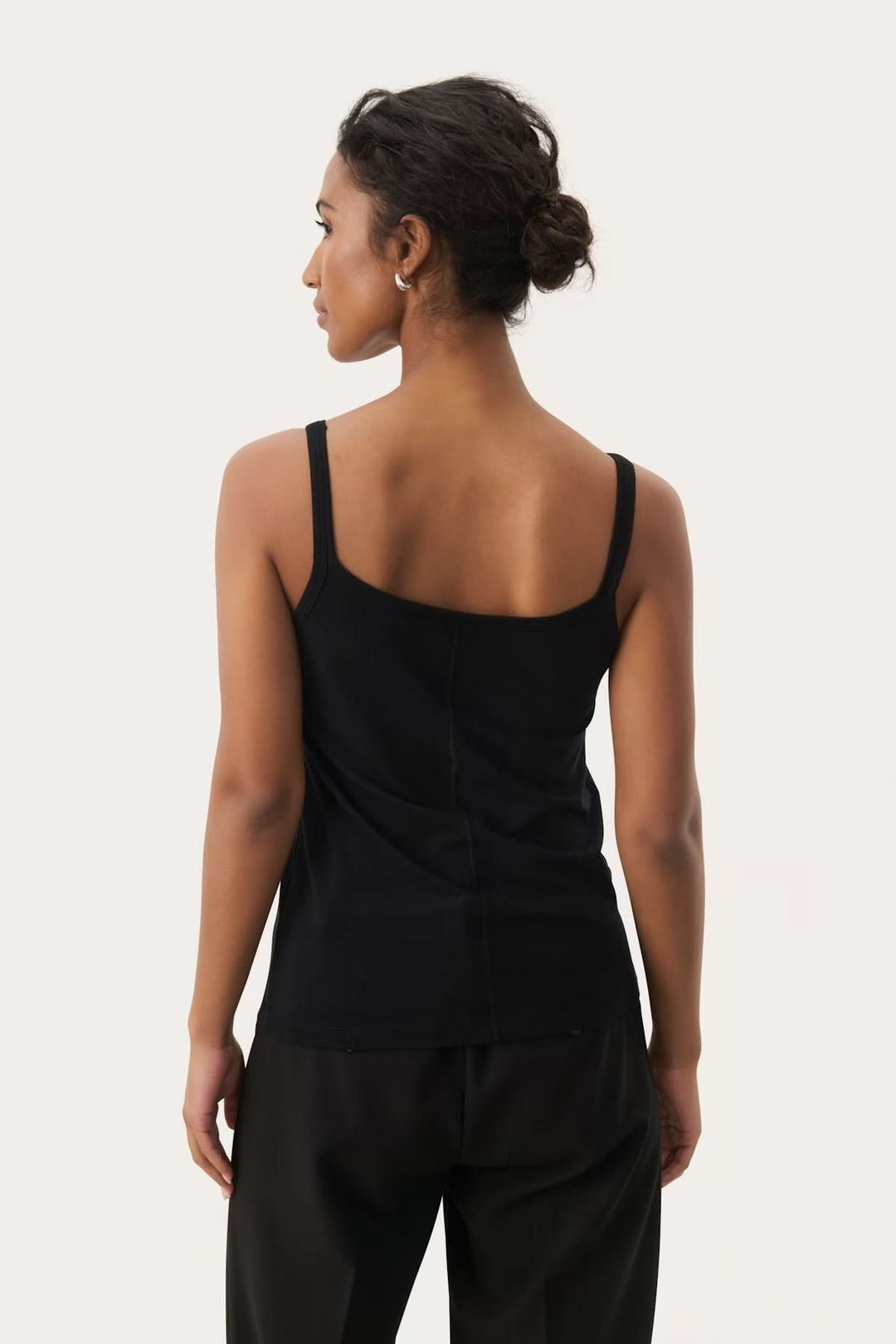 Femme portant une camisole à encolure arrondie noire avec fines bretelles, vue de dos, élégante et ajustée.