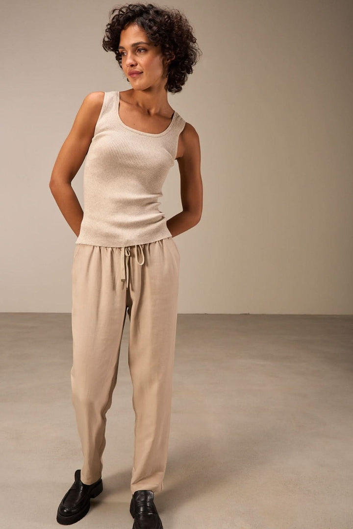 Camisole encolure carrée beige portée avec un pantalon décontracté, mise en valeur d'un look élégant et moderne.