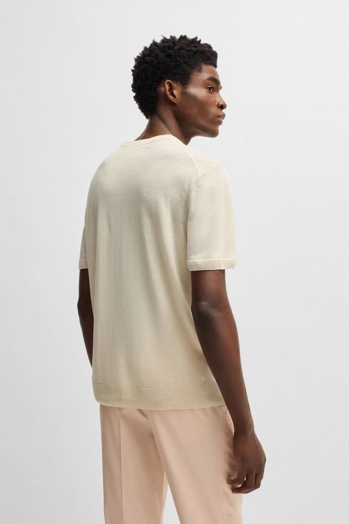 Homme portant un chandail en maille légère à manches courtes, vue de dos, couleur beige, style élégant.