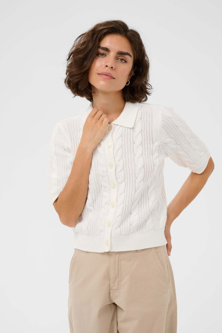 Femme portant le Cardigan Blair en maille torsadée avec col polo et manches courtes, style élégant et soigné.