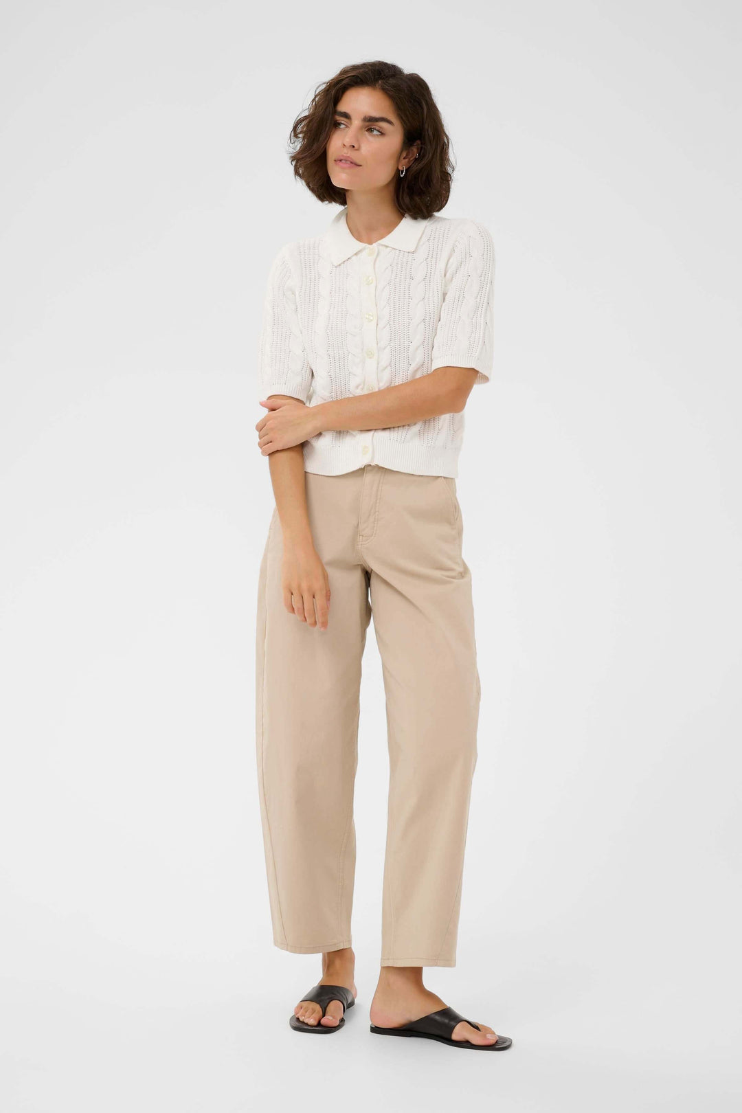 Modèle portant le Cardigan Blair avec coupe ajustée, col polo, et manches courtes, offrant un style élégant et féminin.